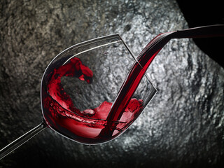 Red wine being served in a glass on black background