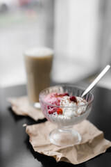 ice cream white and pink in a transparent cream bowl with nuts and berries on a black table