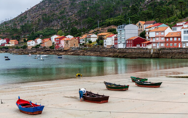 View of the picturesque village of O Pindo in Galicia, Spain, with row boats on the sandy beach and...
