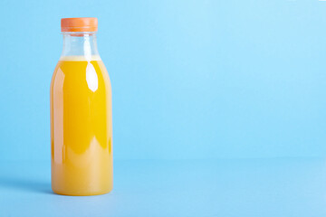 Freshly squeezed orange juice in  bottle on blue background. 