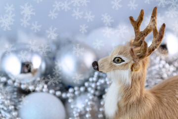 Toy Christmas deer on a background of silvery decorations and white fluffy fur.
