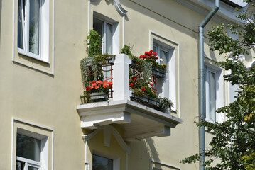 Fototapeta na wymiar Balcony decorated with flowers on the facade of an old building