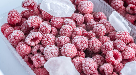 Containers with frozen raspberries in the freezer of the fridge. Concept of frozen food, long term...