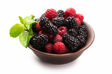 Raspberry, blackberry and mint leaf in ceramic brown bowl isolated on white