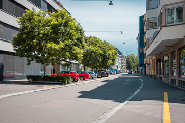 Obraz premium City road with parking cars. Parking with trees and shrubs, city greening.