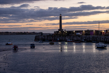 Margate, Kent harbour arm at sunset with lights reflecting on the water. Margate beach, harbour and...