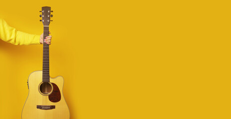 guitar in hand over yellow background, mock-up image with space for text - obrazy, fototapety, plakaty