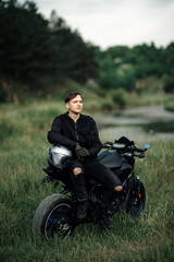 Plakat Photo of biker sitting on motorcycle in sunset on the country road.