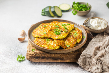 Green zucchini fritters, vegetarian zucchini pancakes with fresh herbs and garlic, served with...