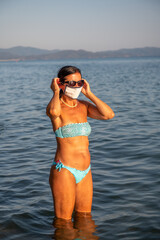 Woman walking on the beach wearing mask in coronavirus times