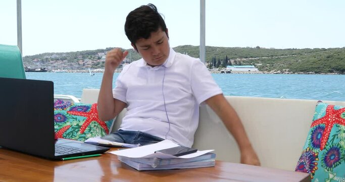 Teenage boy studying on yacht deck Online learning education distance learning for kids at home Homeschooling during quarantine or isolation