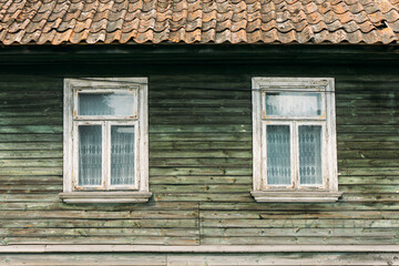Wooden window background. Empty copy space rustic cottage house. Vintage cabin green peeling paint wall. Countryside architecture texture. Red tile roof.