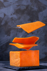 Levitating slices of red Cheddar cheese against the grey background. Flying food