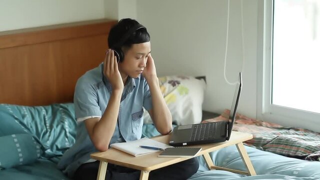 Asian studen study at home listening tutor by laptop taking an online class at home