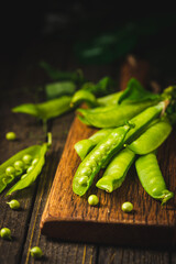Pods of green peas on a old wooden background close up, soft focus