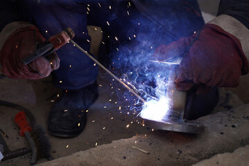 Close-up welder working with electrode at semi-automatic arc welding in manufacture production...