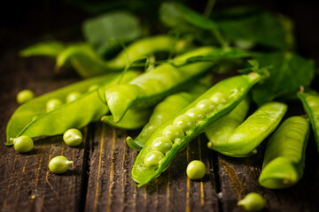 Pods of green peas on a old wooden background close up, soft focus