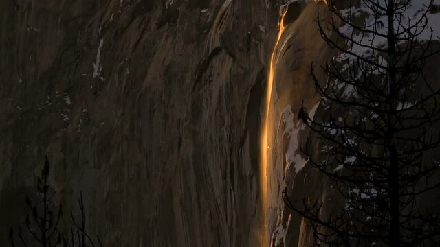 Tilt down shot of Firefall-- seasonal Horsetail Falls illuminated by evening sunlight in Yosemite National Park, California