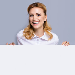 Very happy excited, laughing business woman in confident clothing showing blank banner signboard. Success and advertising concept. Copy space empty place for some text. Blond girl. Square composition.