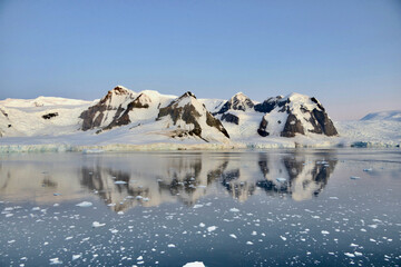 Antarctica, glacier and mountain reflection in ice water, calm evening sunset