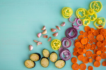 Chopped vegetables - carrots, peppers, onions, eggplant on a wooden table