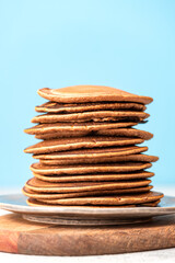 Stack of pancakes in a plate on a light blue background. Free space for text. Traditional breakfast.