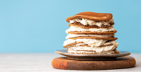 Pancakes with cream in a plate on a blue background. Free space for text. Selective focus. Sweet food. Delicious breakfast, copy space.