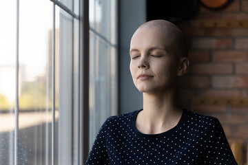 Calm young Caucasian sick hairless woman suffer from cancer meditate relieve negative emotions,...