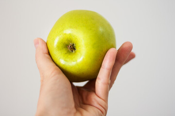 ripe fresh green apple in female hand, healthy food concept, vegetarian diet.
