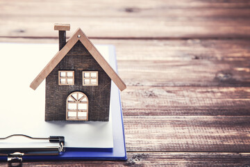 House model with clipboard on brown wooden table