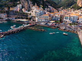 Fototapeta na wymiar Aerial view from the sea of the Amalfi Coast with Amalfi city, Summer day. Travel and vacation to Europe mountains. Boats and ships, the most popular beach. Breakwater. Houses and hotels. Italy