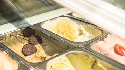 different kinds of ice cream scoop at cafe, Italian gelato with chocolate, pistachio, lemon and tomato flavours. Soft focus, blurred background, film noise