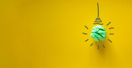 Green paper light bulb. Corporate social responsibility, responsible business, eco friendly, sustainable living concept. Beautiful yellow background. © Dzmitry