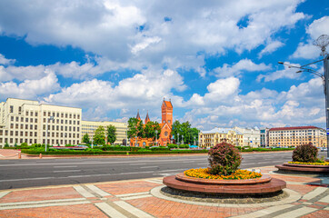 Independence Square in Minsk city centre with Saints Simon and Helena Roman Catholic church or Red Church and Government House, blue sky white clouds in sunny summer day, Republic of Belarus