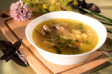 Meat soup with vegetables. soup with pork ribs, herbs and noodles in a white plate on a wooden board.