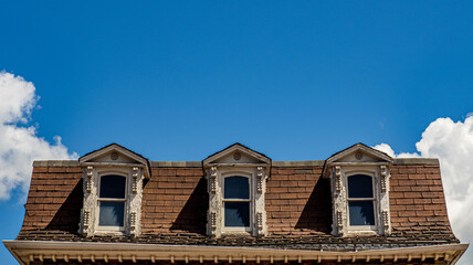 old roof with dormers against blue sky