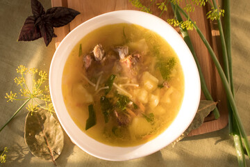 soup with pork ribs, herbs and noodles in a white plate on a wooden board. view from above