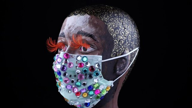 Painted African American woman face mannequin wearing medical fashionably luxury gemstone face mask for protection from viruses and dust, slowly rotating. Urban mask concept prevention from germs.