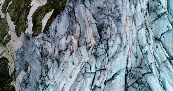 Glacier on the rocks of a mountain, natural landscape from above by a drone, in aerial view. Global warming and climate change concept - 4K