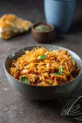 Stewed or braised cabbage served in a bowl on dark stone background, close up