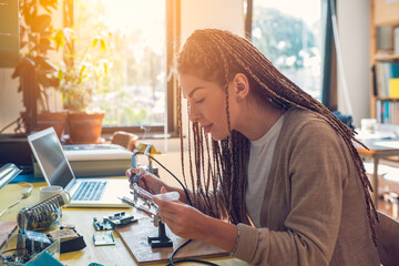 Woman electronics engineer is soldering circuit  board in her workshop stock photo