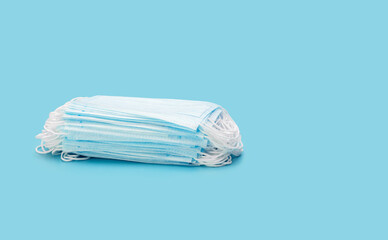 A stack of medical masks on a blue background. Protection and prevention against coronavirus, covid-19 and other viruses. Healthcare concept.