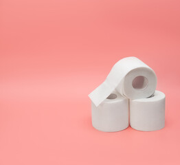Three rolls of toilet paper on a pink background. Side view. Copy space.