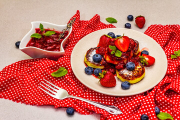 Cottage cheese pancakes with fresh berries and strawberry sauce. Healthy breakfast concept on stone background