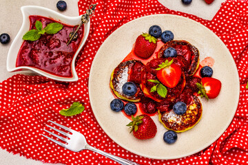 Cottage cheese pancakes with fresh berries and strawberry sauce. Healthy breakfast concept on stone background