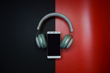 Smartphone in between headphone on black and red background 