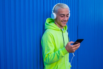one teenager using his phone smiling and having fun looking at it while hearing music with white...