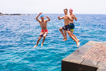 group of friends jumping off together at the beach doing flips and having fun in the water - people...