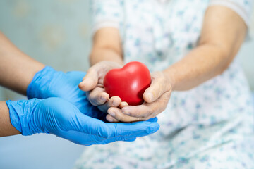 Doctor give red heart to Asian senior or elderly old lady woman patient with love, care, helping, encourage and empathy.