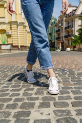 Close up of person walking on paving stone street at summer day